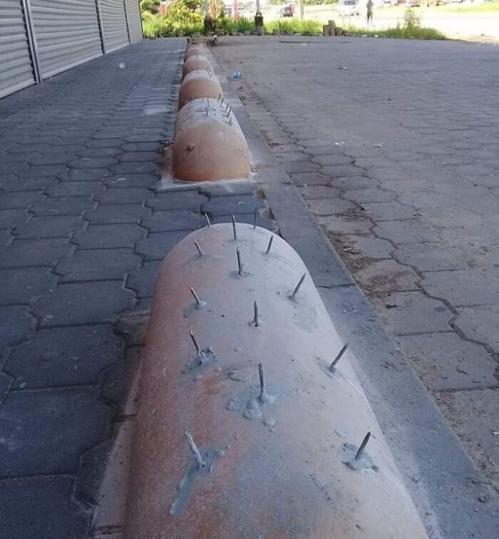 Concrete barrier with dangerous sharp metal spikes protruding, illustrating one of the dangerous designs classified as death traps.