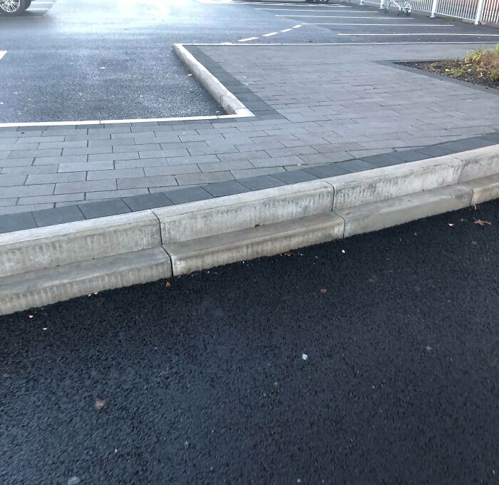 Uneven concrete curb design in a parking lot that could be classified as a dangerous design or death trap.