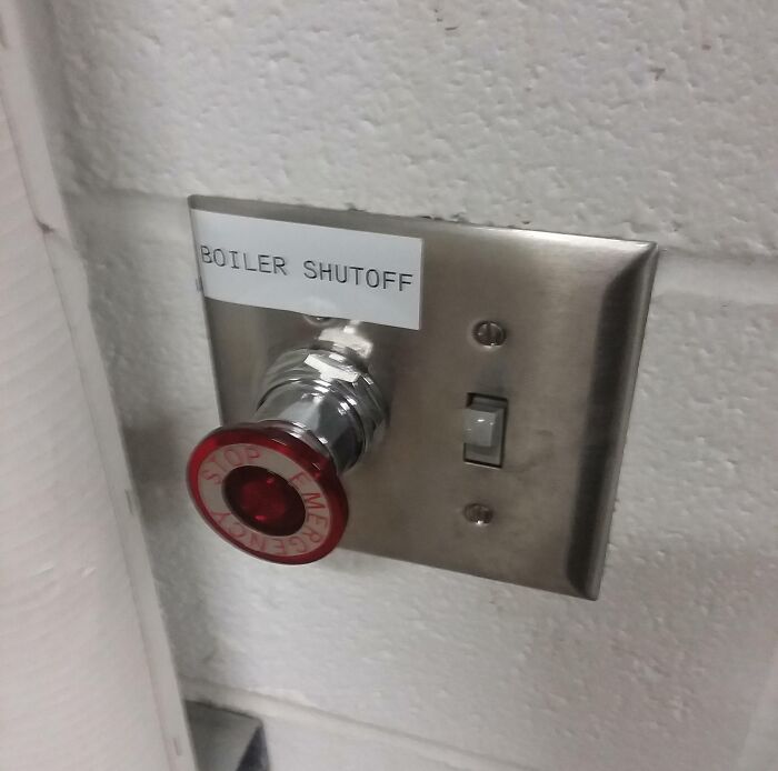 Metal boiler shutoff valve with large red handle and switch on a wall, illustrating one of the dangerous designs death traps.