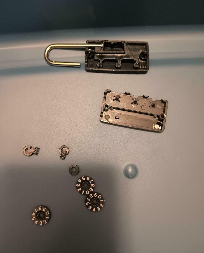 Disassembled combination lock parts scattered on a surface illustrating dangerous designs and potential death traps.