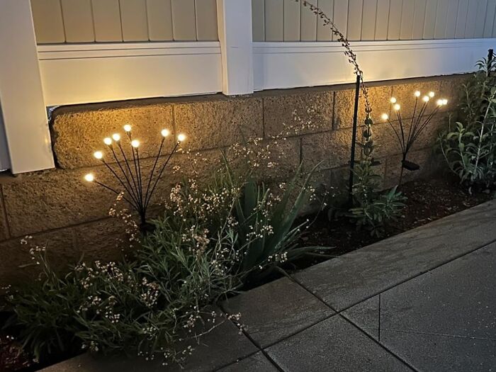 Outdoor garden bed illuminated by decorative lights, calming and enhancing your garden's tiny tantrums at night.