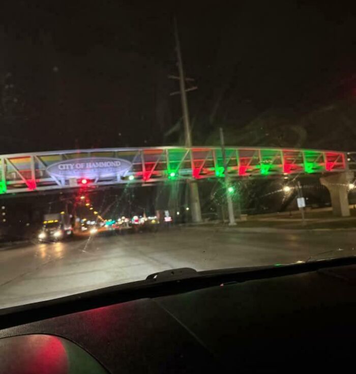 Nighttime view from inside a car of a pedestrian bridge with red and green lights, an example of dangerous designs and death traps.