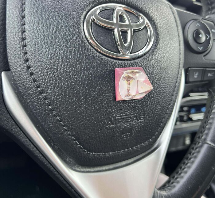 Close-up of a Toyota steering wheel with a small, sharp object attached, illustrating dangerous designs and potential death traps.