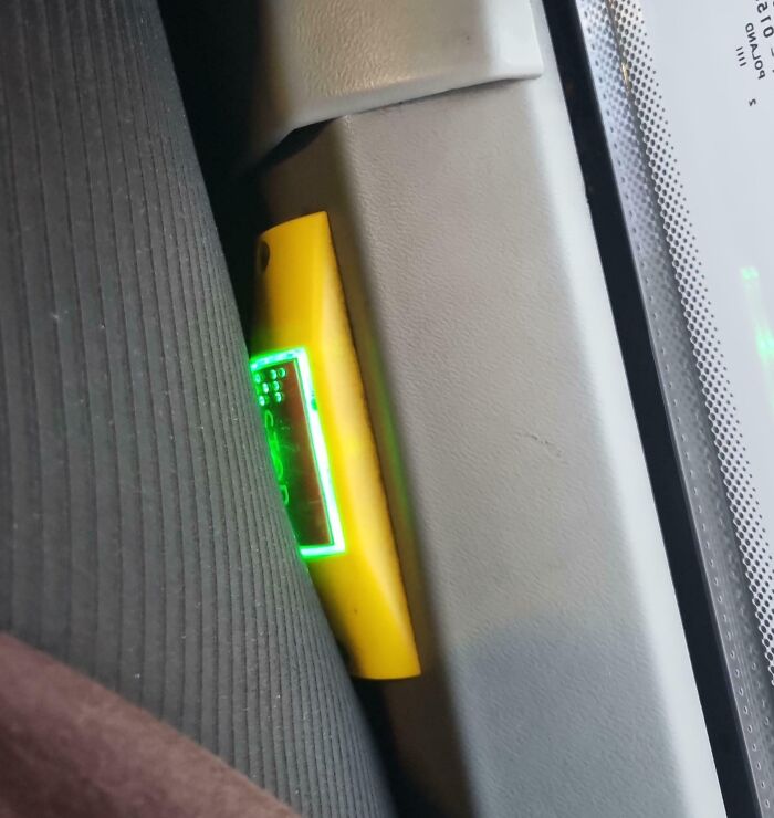 Yellow device wedged between car seat and door frame, illustrating a dangerous design that could be classified as a death trap.