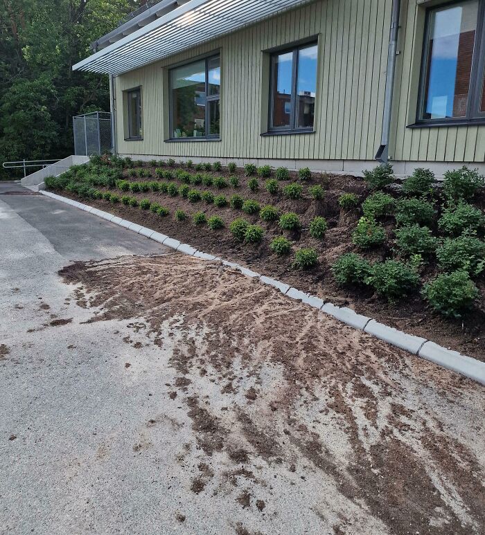 Uneven pavement with loose dirt near building edge, an example of dangerous design and potential death trap hazard outdoors.