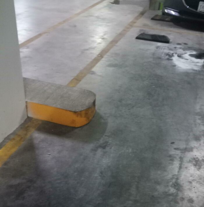 Concrete parking barrier with a raised edge in a garage, a dangerous design that could act as a death trap.