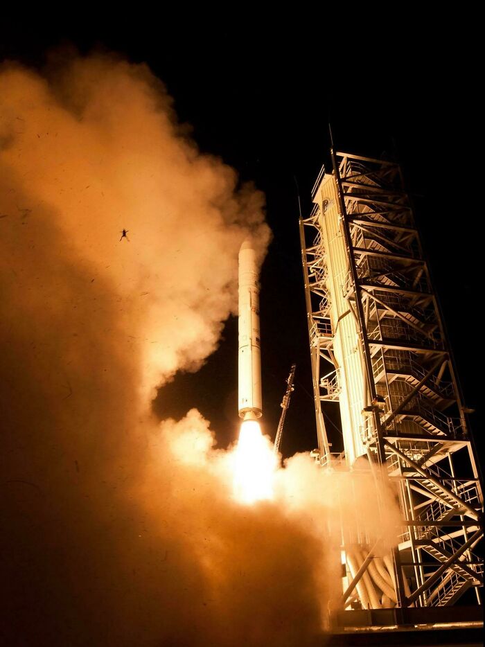 Rocket launching at night with thick smoke and a small figure caught mid-air, showing a hilarious main character moment.
