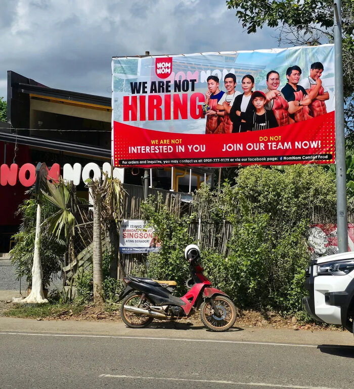 Billboard with people posing muscles and text "We are not hiring" showcasing a hilarious main characters moment.