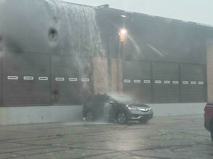 Car caught in water pouring from a broken pipe above, illustrating a worst and hilarious main character moment.