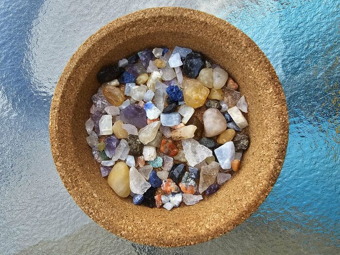 Bowl filled with an unusual collection of various colorful polished stones and crystals at home.