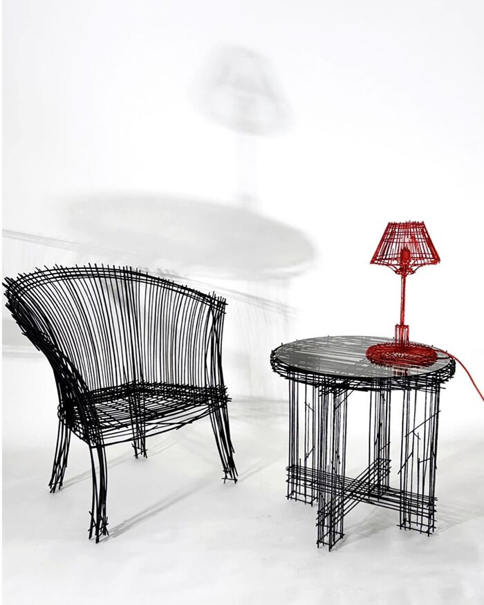 Wire-frame furniture pieces resembling doodles, including a chair, round table, and a red lamp in a minimalist white space.