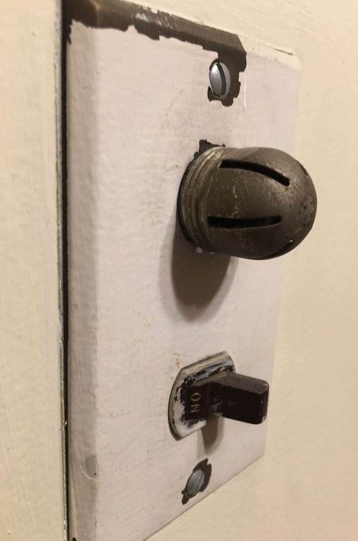 Old unusual light switch with a rusty k**b and toggle in a home with hidden forgotten pasts.