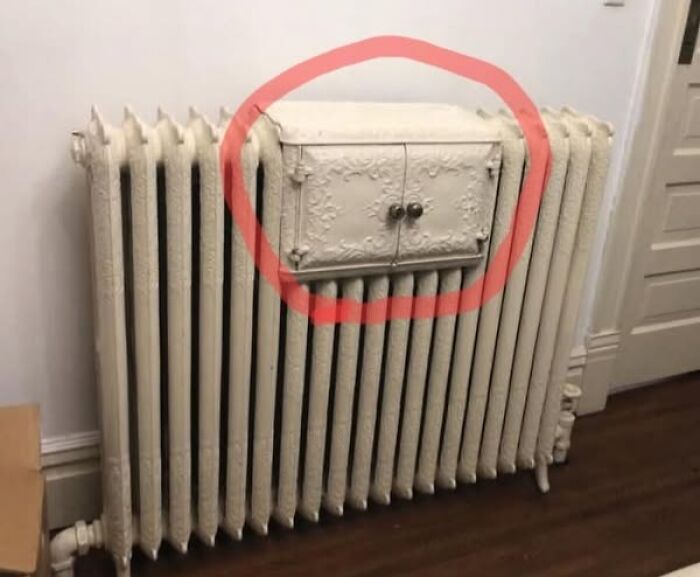 Old cast iron radiator with a hidden ornate cabinet door circled in red, a strange thing found in homes with haunted pasts.