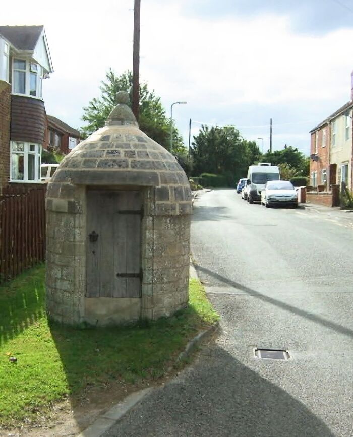 Small stone structure with a wooden door beside a suburban road, a strange thing found in homes with hidden pasts.