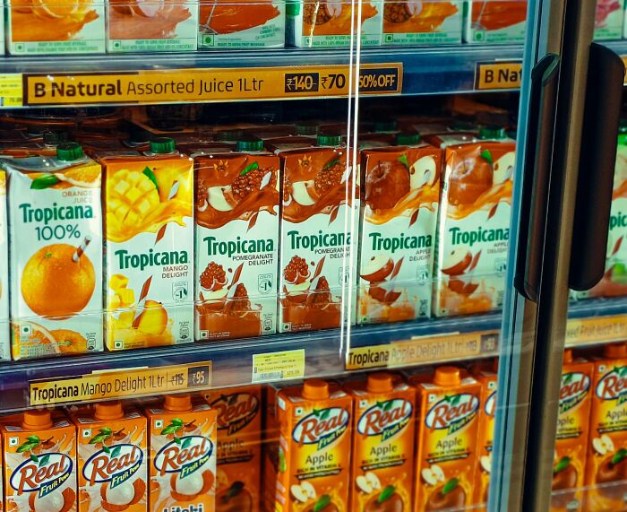 Refrigerated juice cartons in a grocery store showing product variety for side-by-side comparisons of food prices.