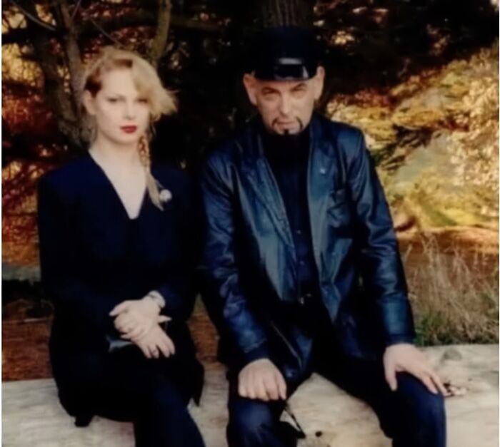 Two people dressed in dark clothing sitting outdoors surrounded by autumn trees, evoking outrageous hot takes vibe.