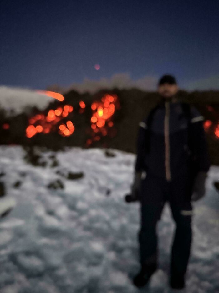 Person outdoors at night with blurry snow and glowing fire in the background, illustrating mildly infuriated moments that ruined mood.
