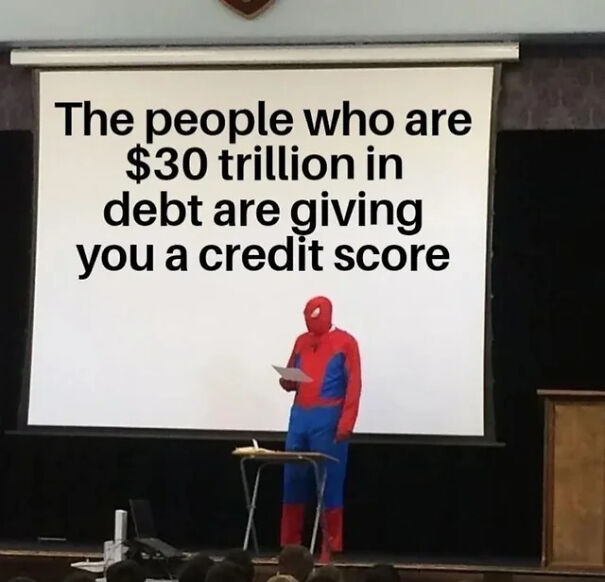 Person dressed as Spiderman presenting a slide critical of capitalism and debt with main SEO keywords capitalism hate.