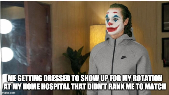 Person in Joker makeup and gray Nike hoodie standing indoors, illustrating medical school memes about future doctors' struggles.