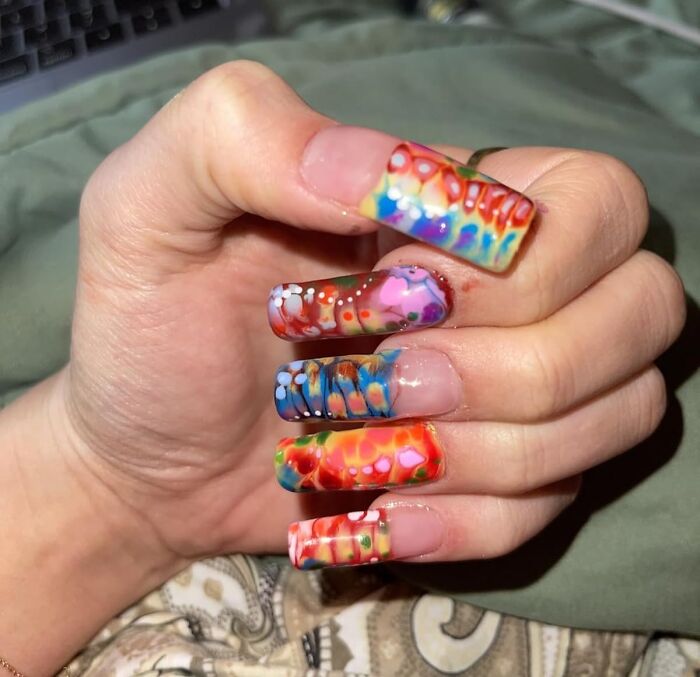 Hand with colorful and artistic nail designs featuring vibrant patterns perfect for a summer glow up look.