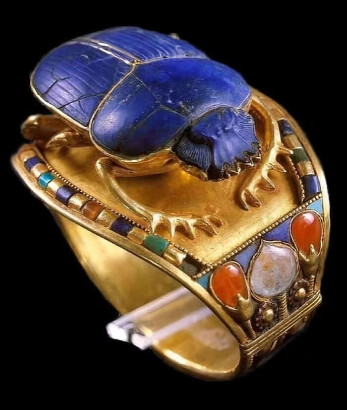 Ancient gold ring featuring a detailed blue scarab beetle, showcasing archeology and art in historic craftsmanship.