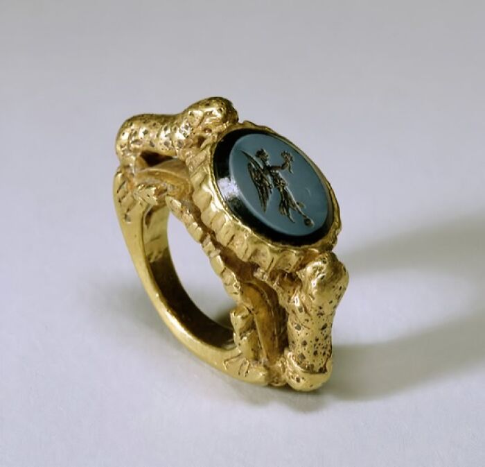 Ancient gold ring with engraved gemstone depicting a winged figure, an archeological art wonder from historic times.