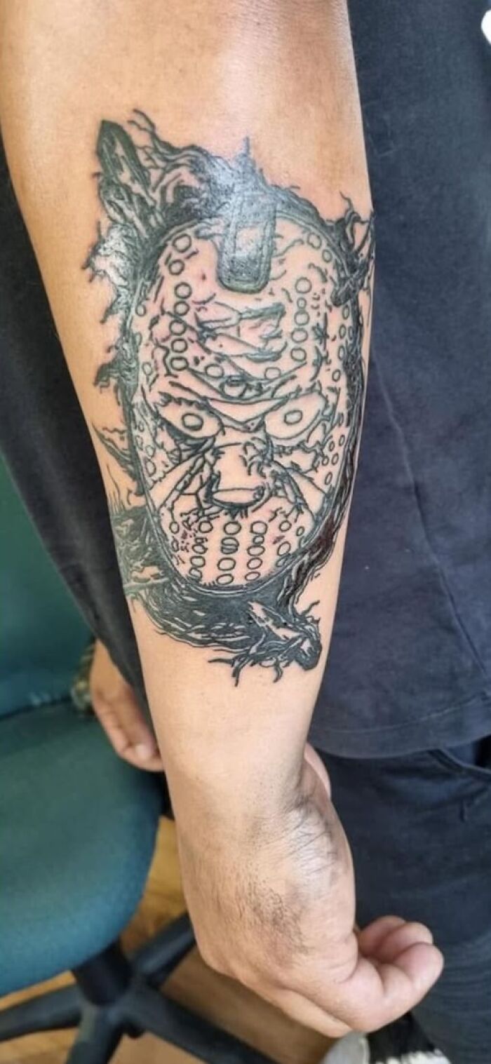 Forearm tattoo of a horror mask with detailed linework, showcasing a cool ink design with a permanent mistake.