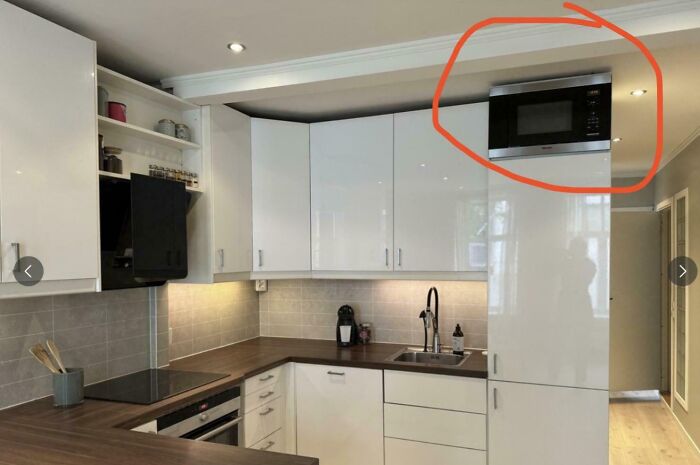 Modern kitchen showing a poorly placed microwave above tall cabinets, highlighting dumb interior design decisions.