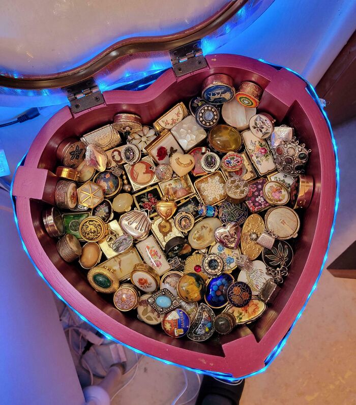 Heart-shaped box filled with an unusual collection of vintage pillboxes in a home setting with blue LED lighting.