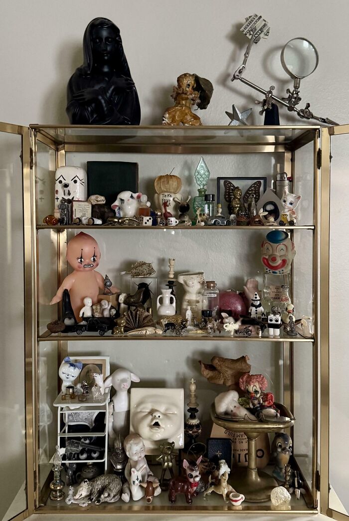 Glass display case filled with unusual and interesting collectibles and figurines in a home collection.