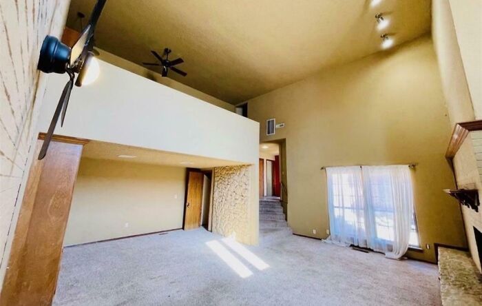 Spacious living room with high ceilings and carpet flooring showcasing dumb interior design decisions and poor layout choices.
