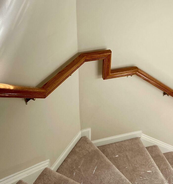 Wooden stair handrail with sharp angled corners showing dumb interior design decisions and poor common sense.