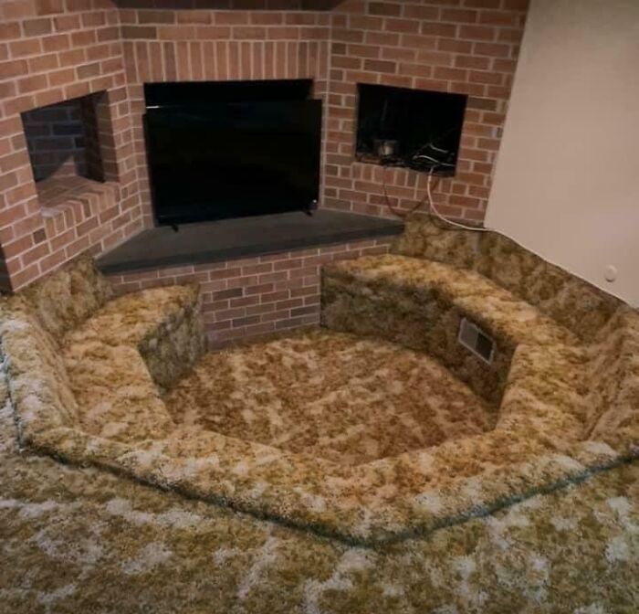 Sunken living room with all carpeted seating and floor in a small brick-walled space showing dumb interior design decisions.