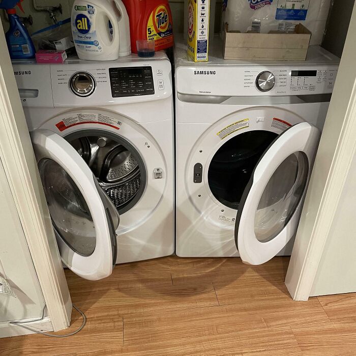 Two front-loading Samsung washing machines side by side with doors open in a small laundry space.