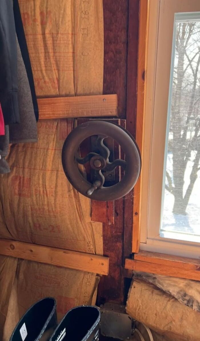 Old vintage valve wheel mounted on wooden wall inside a home with hidden forgotten past and insulation exposed