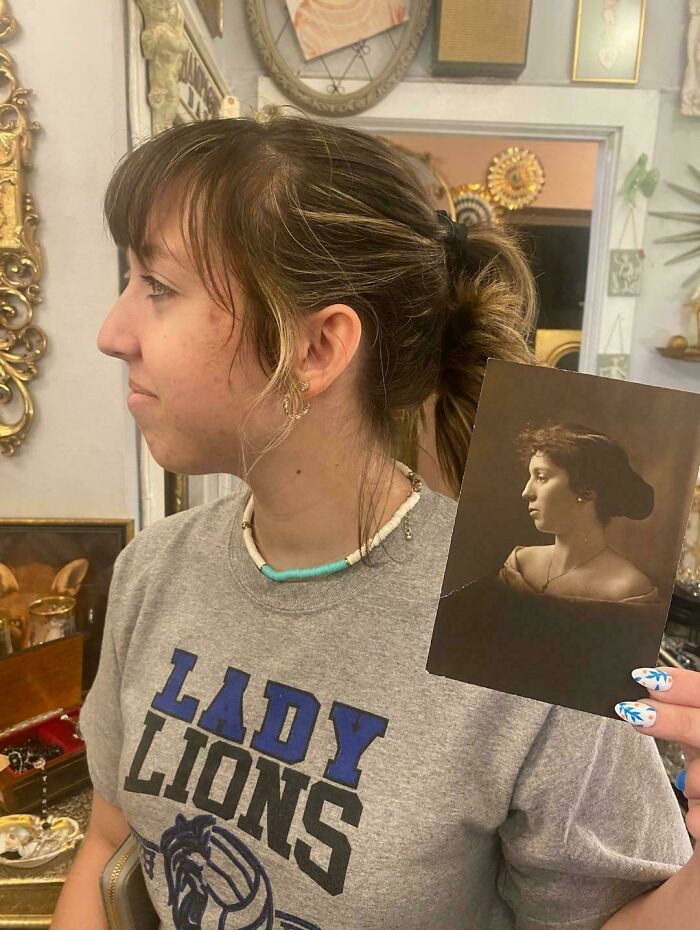 Young woman holding a vintage portrait photo, highlighting people share found photos in a cozy room with decorations.