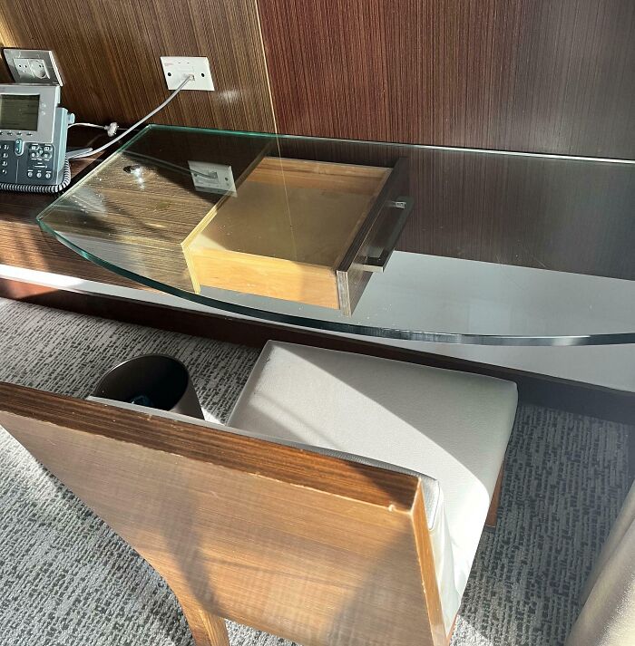 Curved glass desk with drawer mounted underneath, revealing a dumb interior design decision lacking common sense.