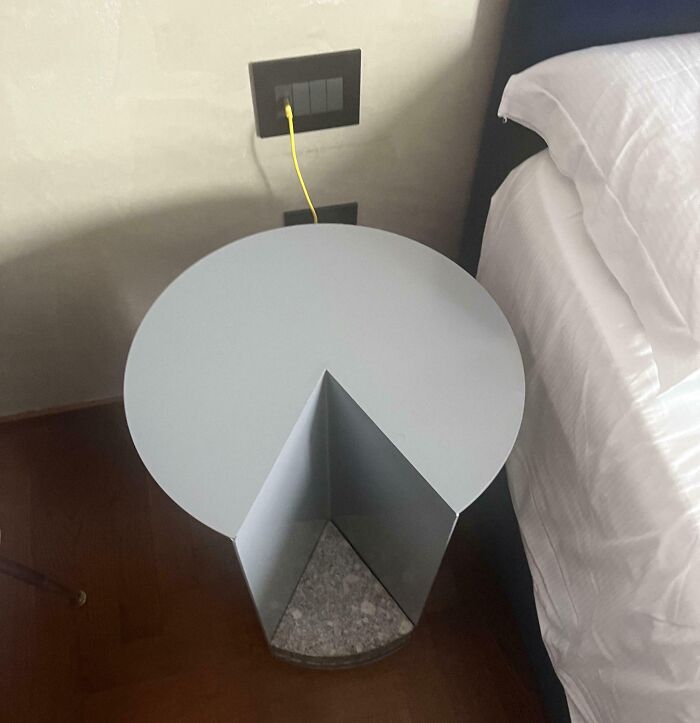 Round side table positioned awkwardly around a corner by the bed, showcasing a dumb interior design decision.