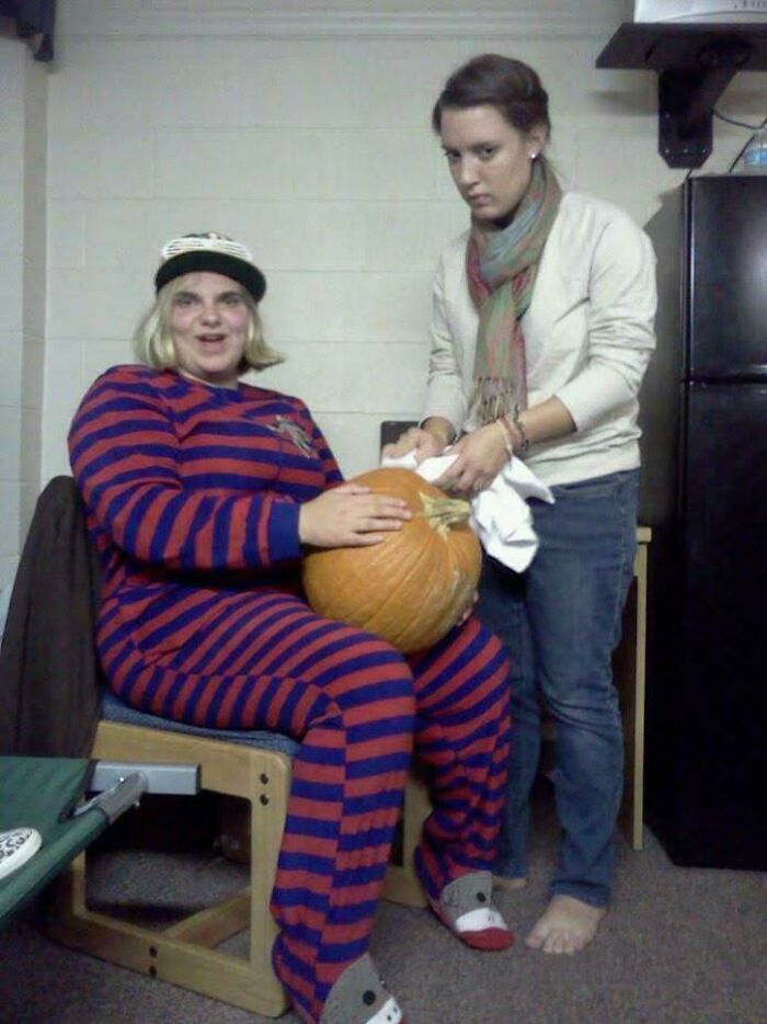 Two people share a moment indoors with one holding a pumpkin and the other wiping it, capturing a candid found photo.