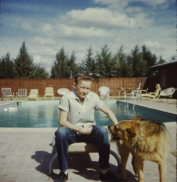 Boy sitting by the pool with his dog on a sunny day, capturing a moment from found photos people share.