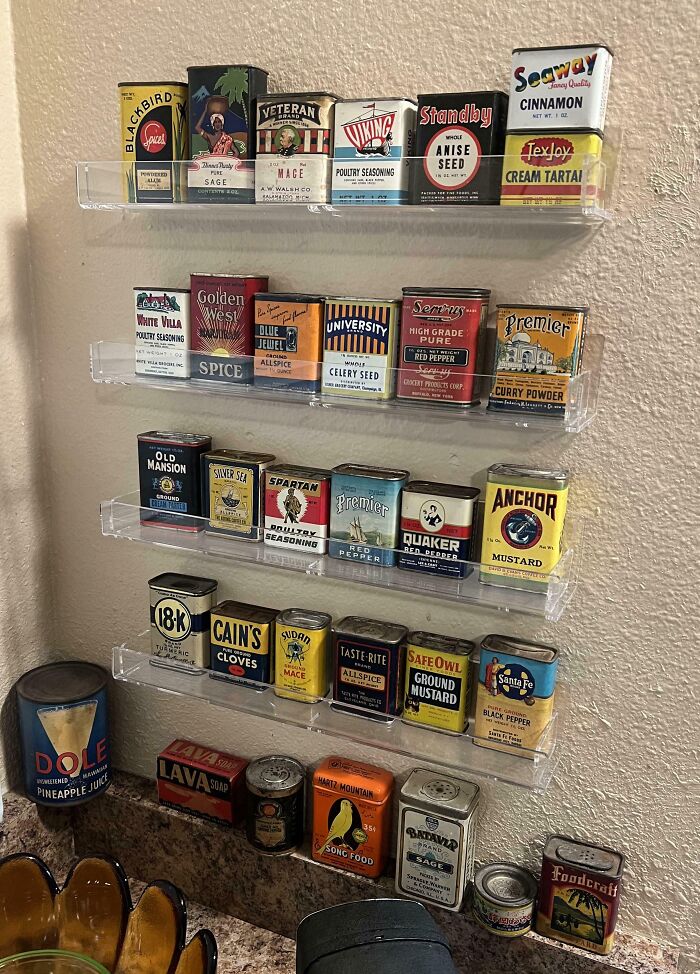 Vintage spice and seasoning tin collection displayed on clear shelves in a home, showcasing unusual home collections.
