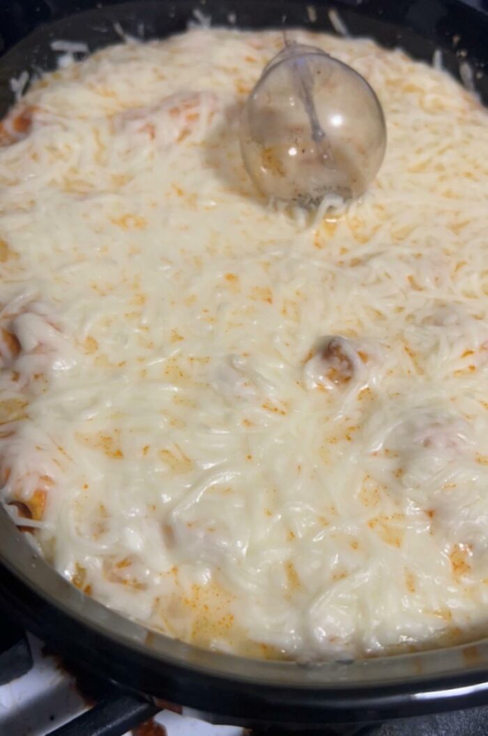 Pan full of melted cheese and sauce with a plastic bubble melted into it, illustrating cooking fails and accidents.