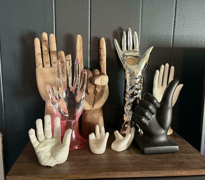 Collection of unusual hand sculptures and models displayed on a wooden surface in a home setting.