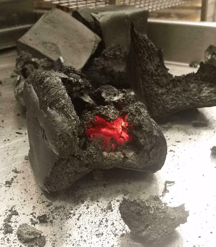 Burnt charcoal remains glowing red on a metal surface, illustrating a dramatic cooking fail and accident.
