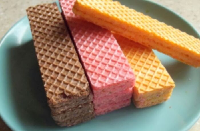 Colorful nostalgic wafer cookies stacked on a blue plate, evoking memories from past decades.