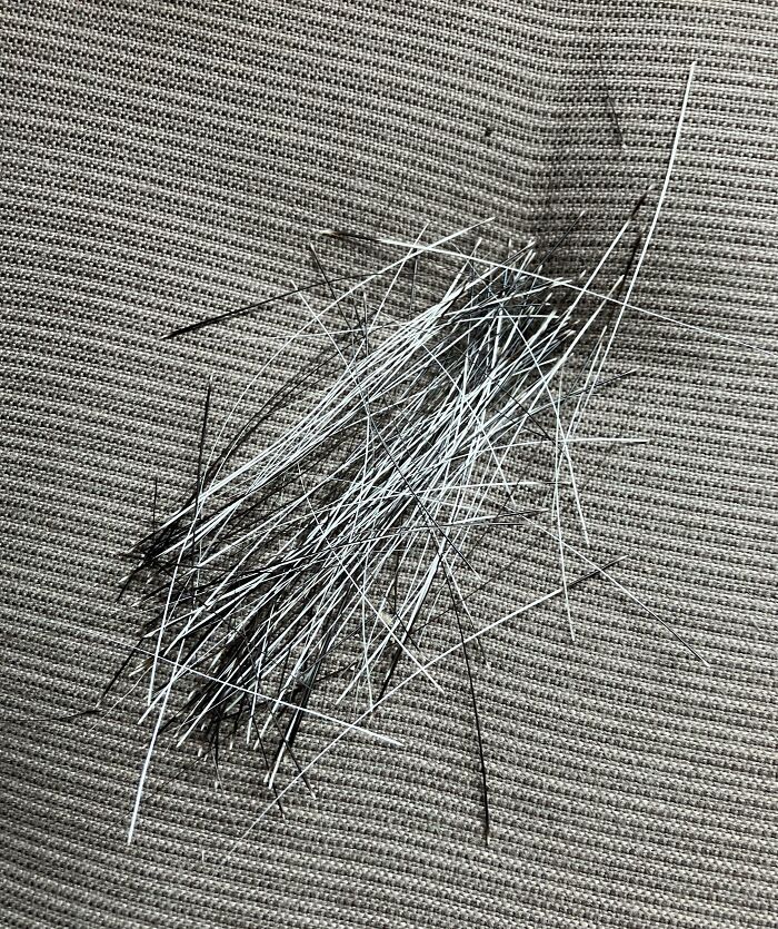 Collection of thin black and white needles arranged on a textured fabric surface in a home setting.