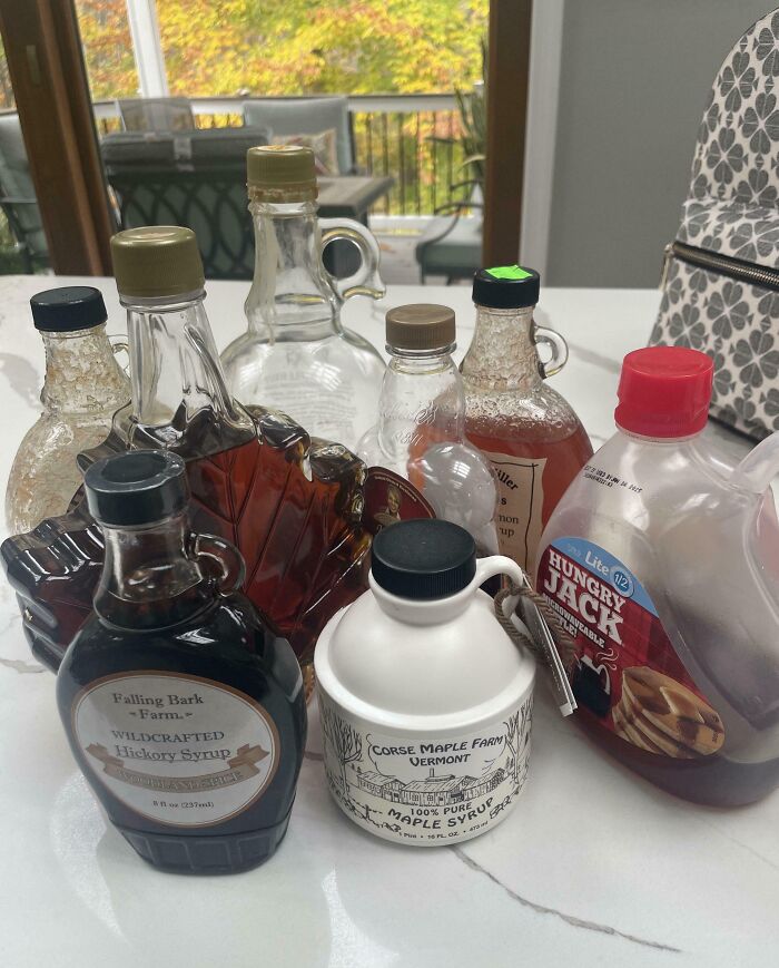 Collection of unusual maple syrup bottles displayed on a kitchen counter in a home setting.