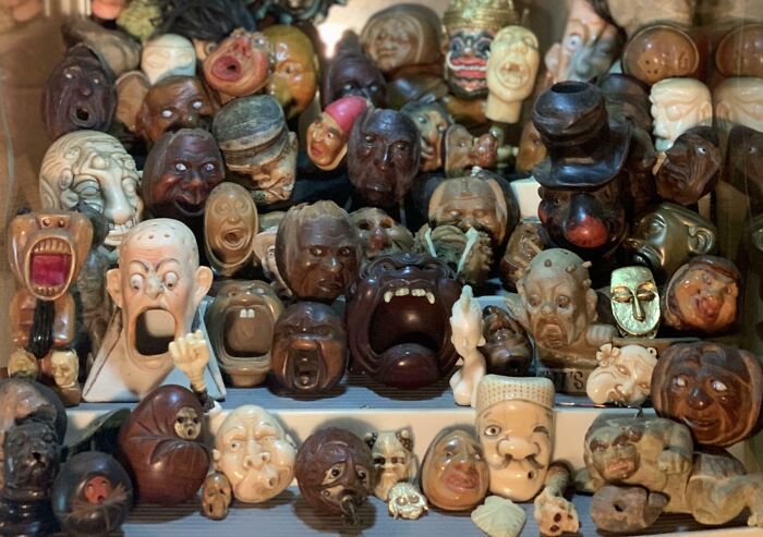 Collection of unusual and interesting carved face figurines displayed as part of a unique home collection.