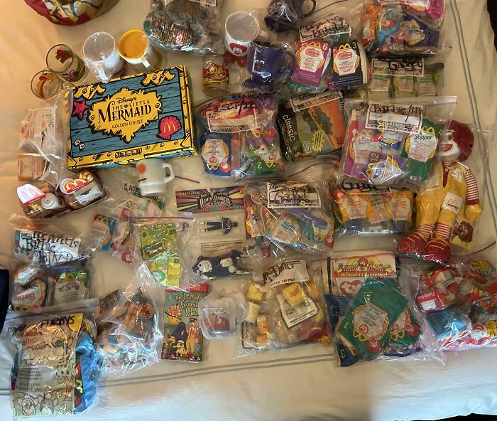 Collection of unusual and interesting McDonald's toys and memorabilia displayed on a bed in clear plastic bags.