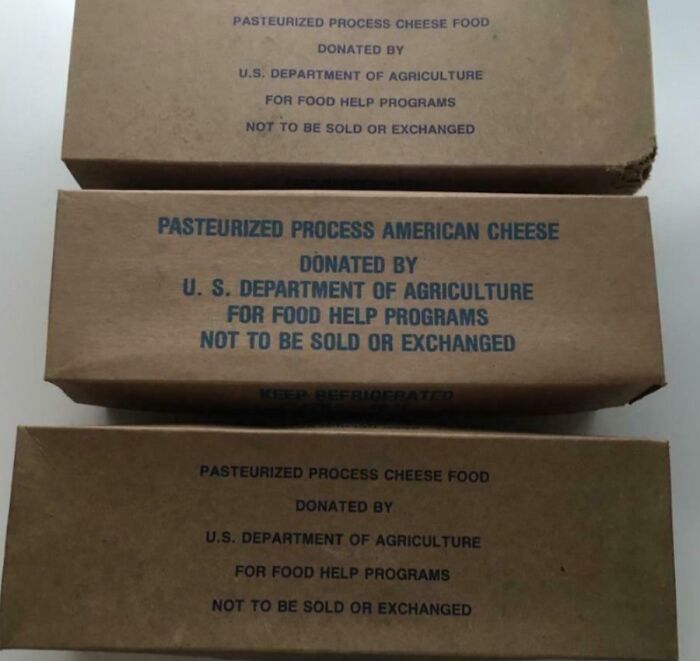 Three vintage cardboard boxes of pasteurized process cheese donated by USDA for food help programs, nostalgic photo.